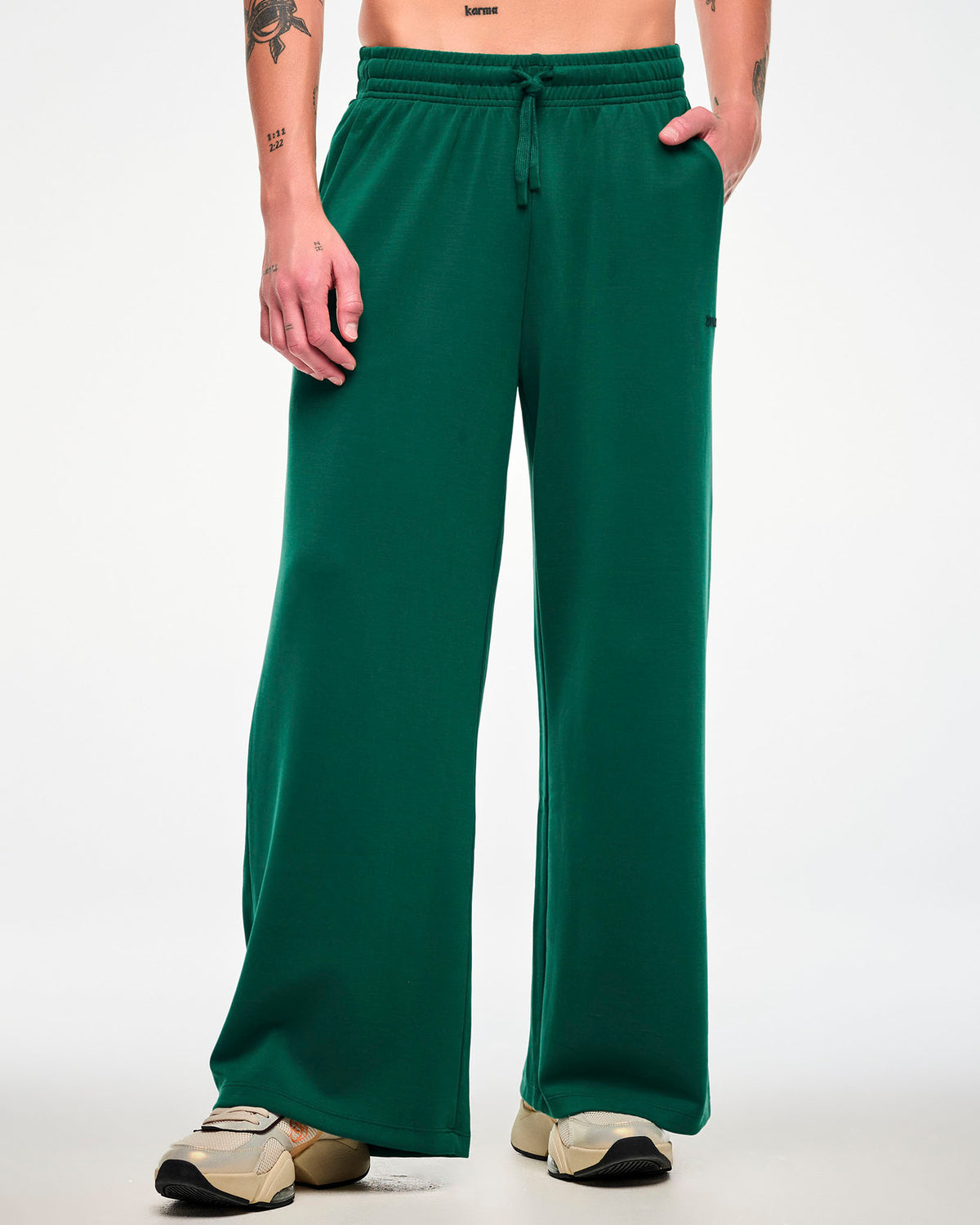 Male model in teal green high-waisted straight-leg pants with a drawcord waist paired with beige shoes.