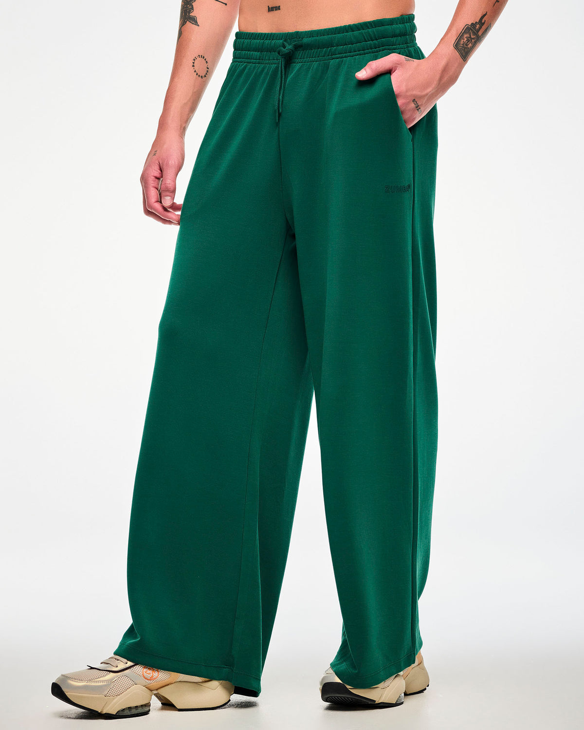 Male model in the teal green high-waisted pants, turned slightly to show the wide, relaxed leg, paired with beige platform shoes.