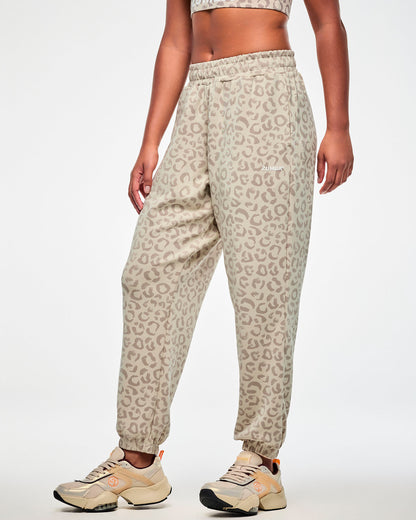 Female model in the beige leopard print slouch cargo pants, turned slightly to show the relaxed leg and gathered ankle cuffs, paired with a matching bra and beige shoes.