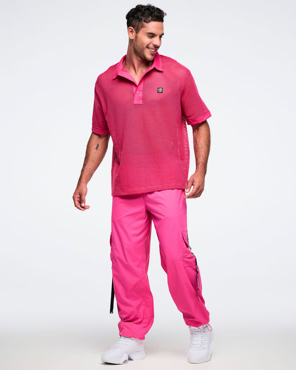 Male model wearing a pink mesh polo with matching pink cargo pants and white shoes.