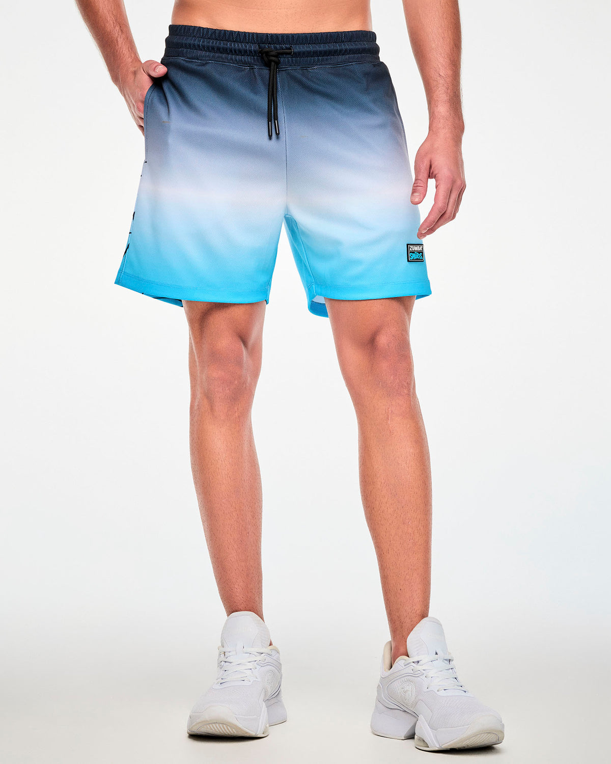 Male model in the navy-to-light-blue ombre mesh shorts with one hand in the pocket, paired with white shoes.