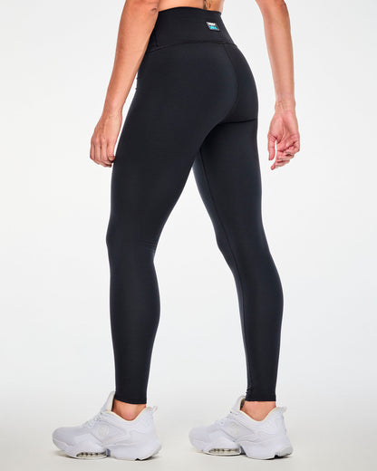 Back view of a female model in the black leggings, showing a plain back and a small 'ZUMBA' and 'THE SMURFS' patch on the back of the waistband.