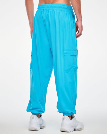 Back view of a male model in the aqua blue cargo pants, showing the gathered elastic waistband, a plain back, and a cargo pocket on each leg.