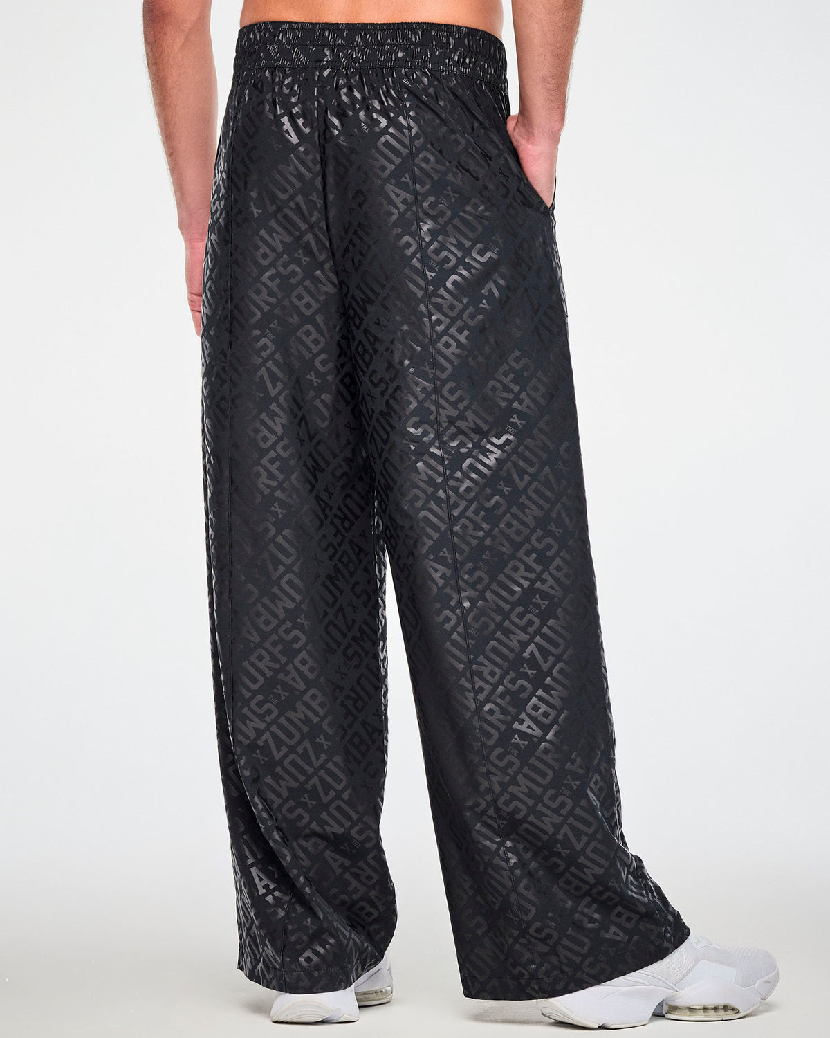 Shown from the back, a male model in the black wide-leg pants, with the tonal logo print covering the full back and a relaxed, straight wide leg.
