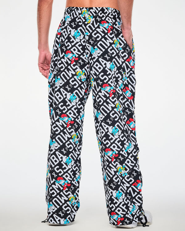 Back view of a male model in the black and white Smurfs print cargo pants, showing the elastic waistband, a cargo pocket on each leg, and black drawcords at both hems.