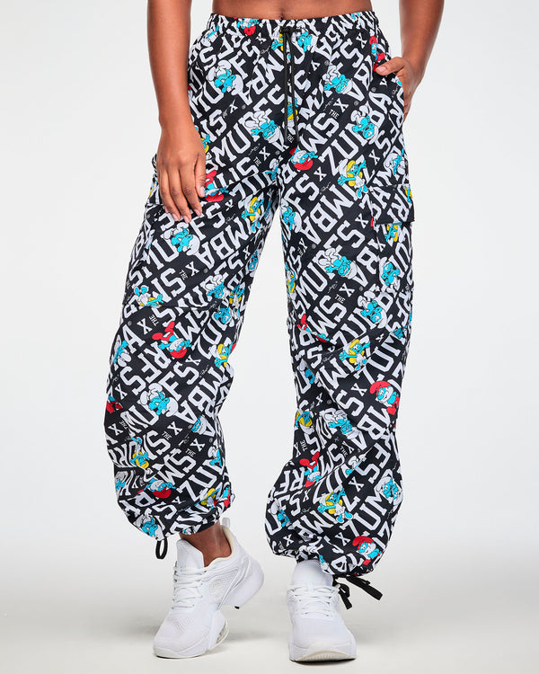Full view of a female model in the black and white Smurfs print cargo pants with the hem drawcords pulled tight, paired with white shoes.