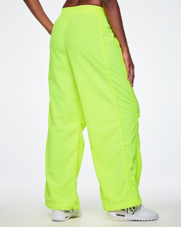 Back view of a female model wearing bright neon yellow-green wide-leg cargo pants, paired with white shoes.