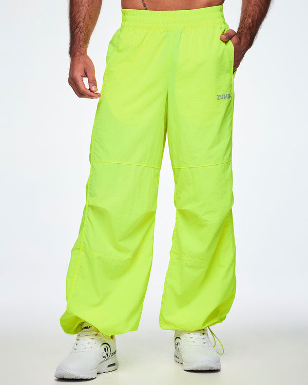 Front view of a male model wearing bright neon yellow-green Zumba pants with white shoes.