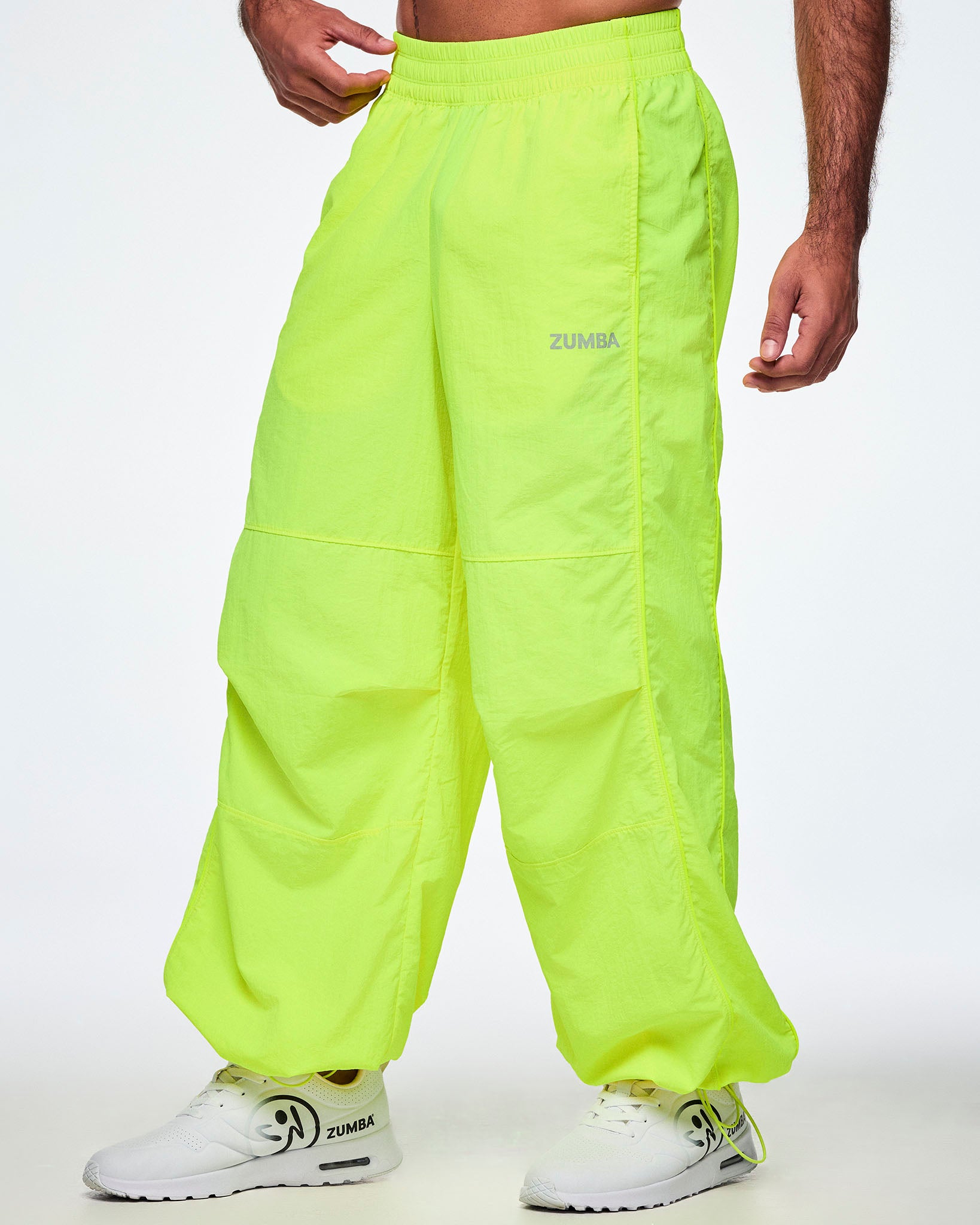 A male model wearing bright neon yellow-green Zumba pants with white shoes.