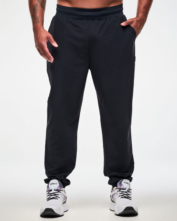 Male model wearing high waisted black jogger pants, paired with white shoes.