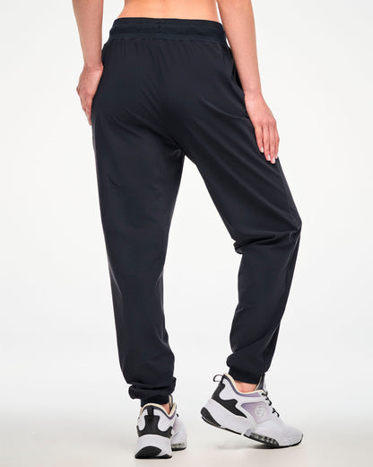 A female model shown from the back wearing high waisted black jogger pants and white athletic shoes.