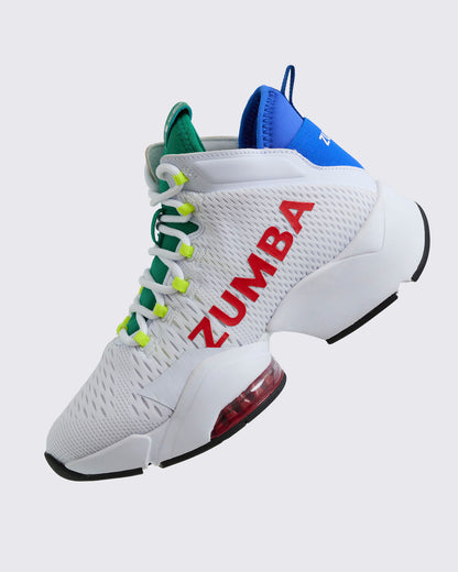 Lateral profile of white Zumba high-top sneaker with red “ZUMBA” logo, green tongue, neon yellow eyelets, blue heel collar, black outsole, and red air unit in the heel, on a light gray background.