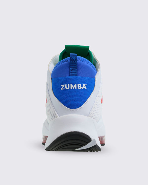 Rear view of the sneaker showing blue heel panel with white “ZUMBA” text, green inner collar, white upper, and thick white heel with black outsole, on a light gray background.