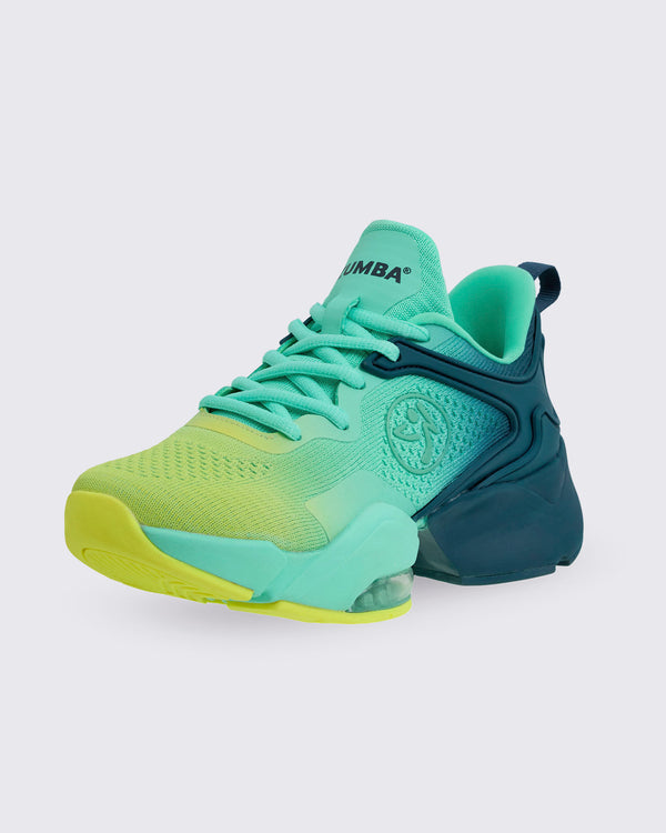 Teal-to-yellow gradient Zumba low-top dance sneaker with mint laces, textured knit upper, molded navy heel and cushioned sole with visible air unit, photographed on a light gray background.
