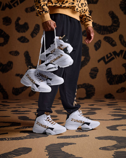 White high-top sneakers with leopard logo detail on male model in black joggers and a tan leopard print sweatshirt.