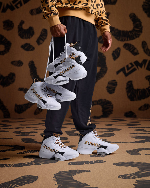 White high-top sneakers with leopard logo detail on male model in black joggers and a tan leopard print sweatshirt.