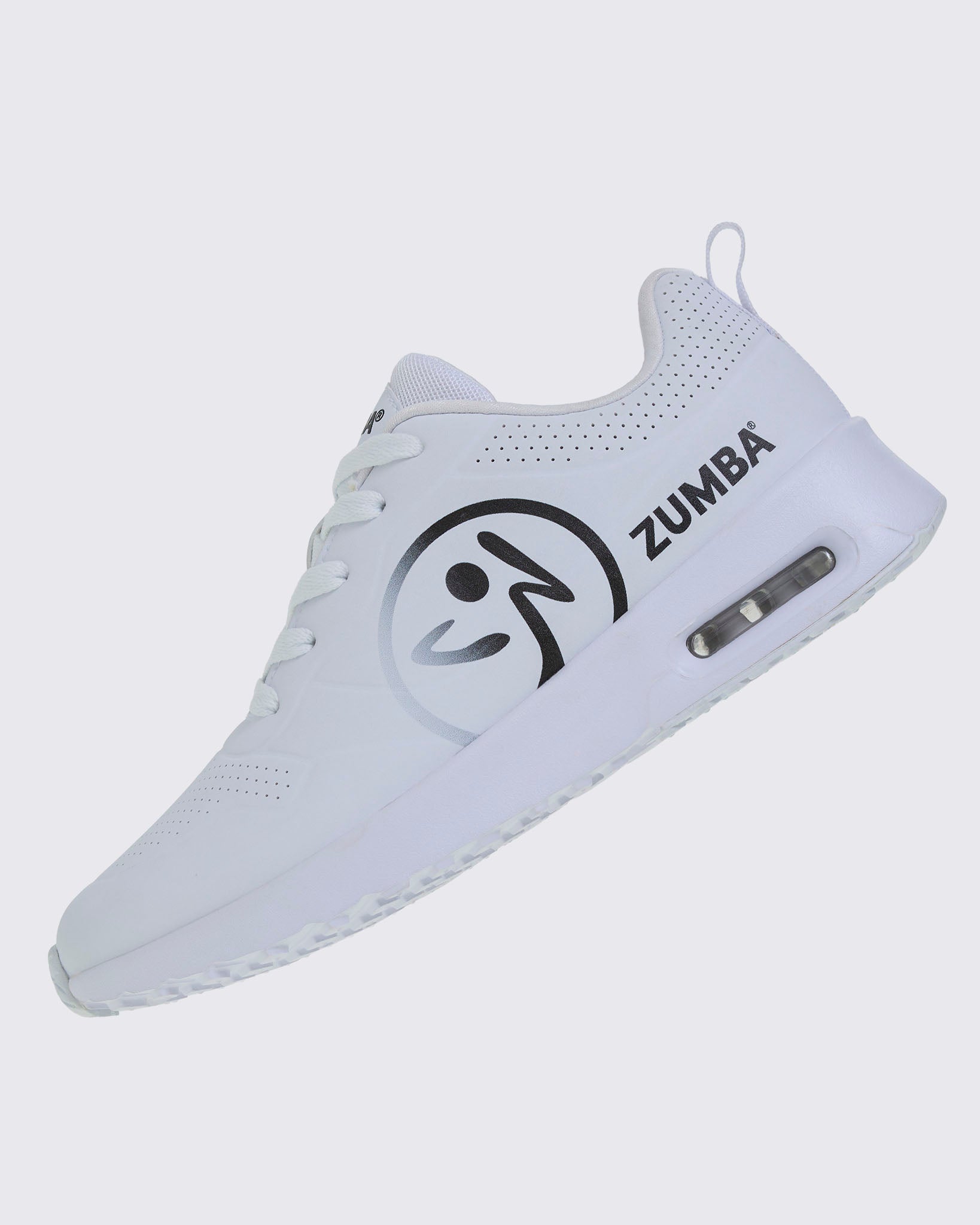 Left angled view of a white Zumba sneaker with a large black Zumbito and black Zumba text on a white background.