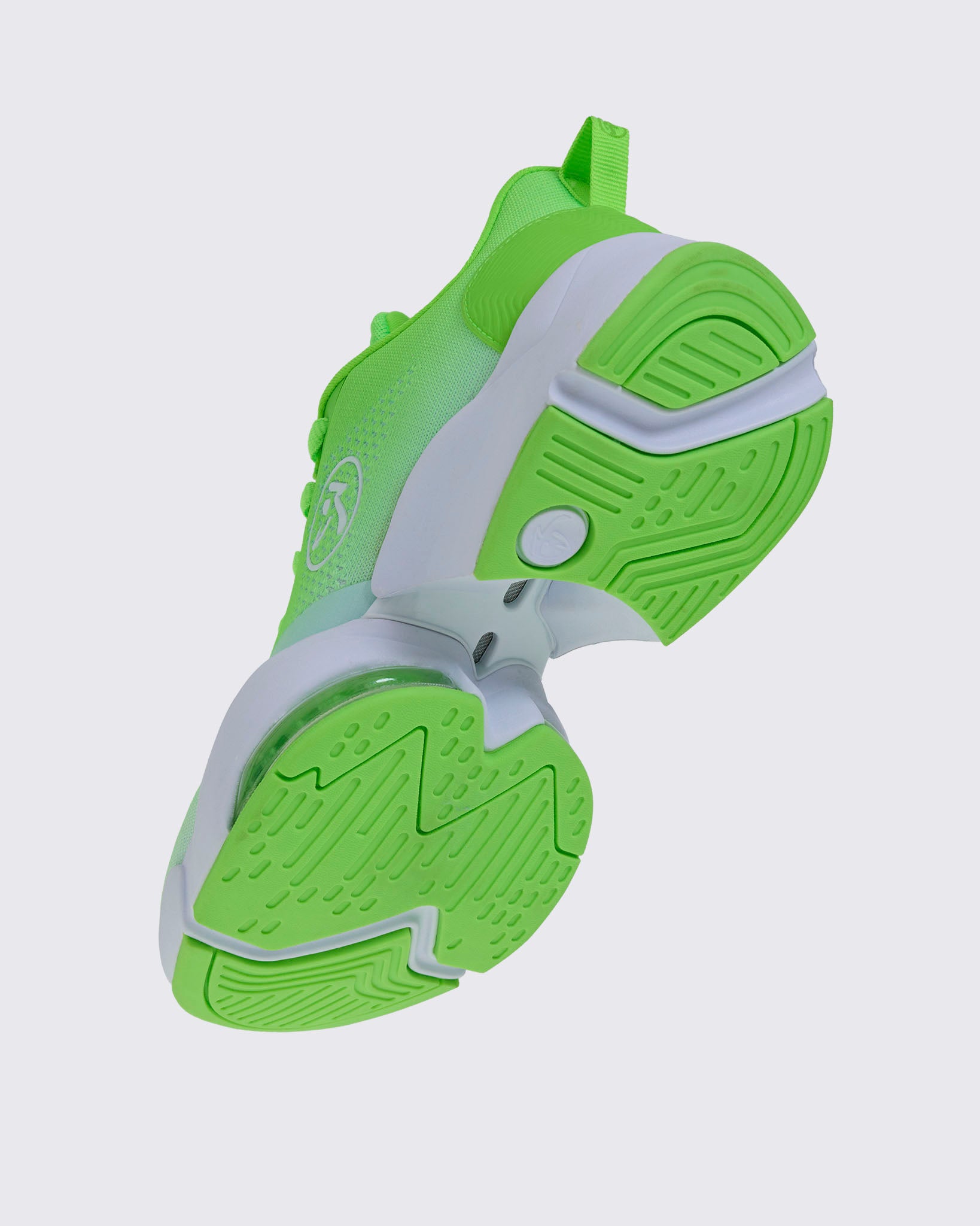 Angled underside view of a neon green sneaker showing the textured outsole and heel, with a white midsole panel and a Zumbito logo imprint on the upper heel.