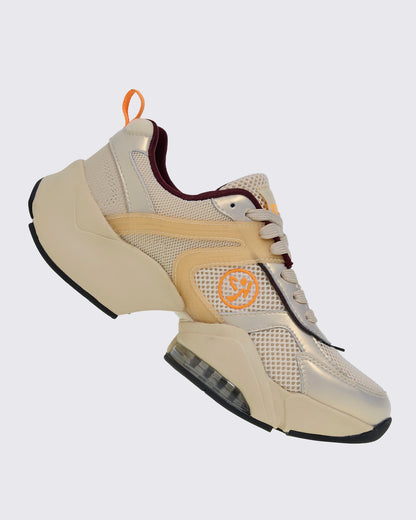 Right side view of a beige platform shoe, showing an orange Zumbito logo on the mesh side panel, curved translucent tan overlays, and a clear air cushion in the sole.