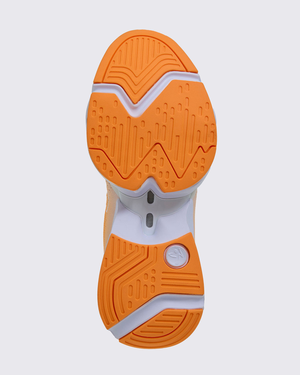 Sole view of the shoe, showing orange grooved tread split into forefoot and heel sections on a white sole, with a white Zumbito logo disc at the heel.