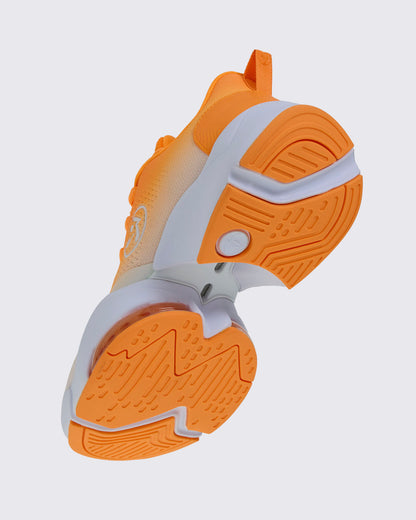 Angled underside view of the shoe, showing the orange tread, a white sole with an open gap under the arch, and a clear air cushion near the toe.