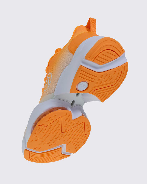 Angled underside view of the shoe, showing the orange tread, a white sole with an open gap under the arch, and a clear air cushion near the toe.