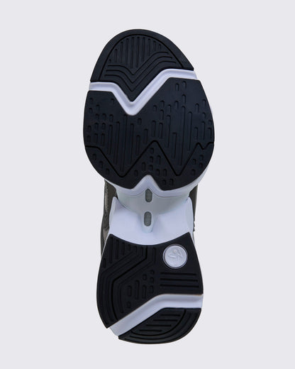 Sole view of the shoe, showing black grooved rubber tread split into forefoot and heel sections on a white sole, with a white Zumbito logo disc at the heel.