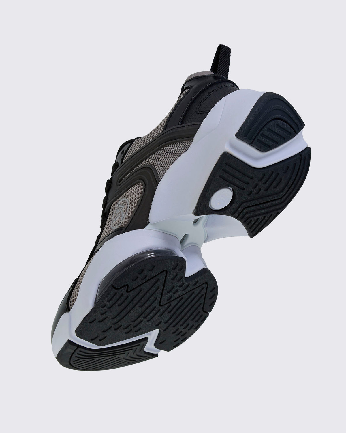Angled underside view of the shoe, showing the black tread, a white sole with an open gap under the arch, and a clear air cushion near the toe.