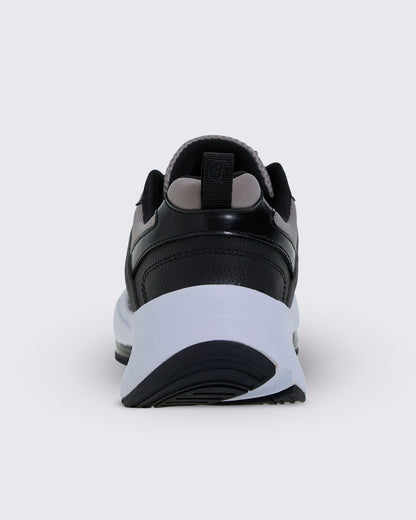Heel view of the shoe, with a black perforated heel panel, a black pull tab with a Zumbito logo, grey lining, and a thick white sole over black tread.