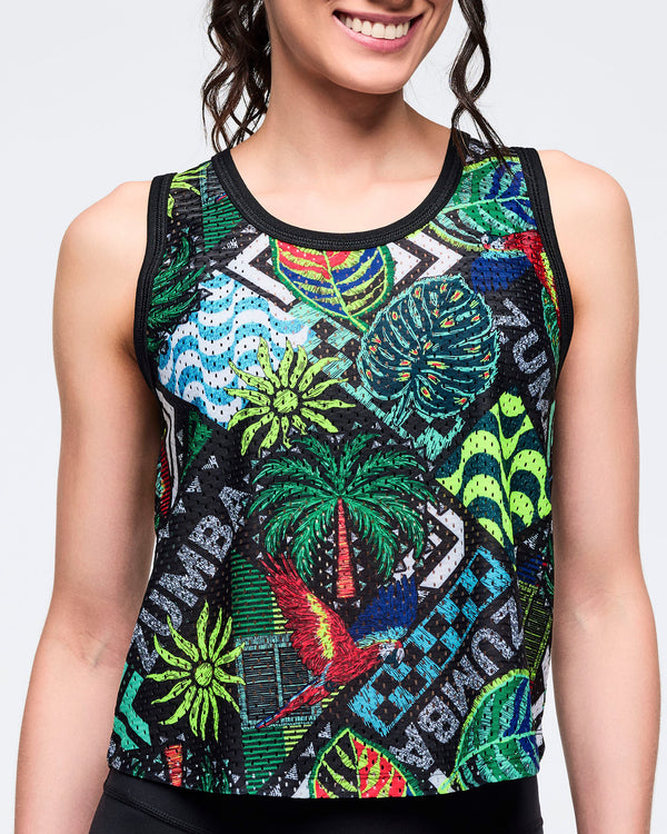Close-up of the tropical-print sleeveless tank showing the multicolor jungle-inspired pattern and black neckline trim on a female model against a white background.
