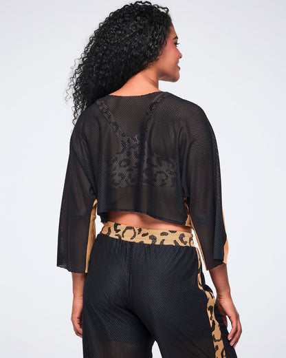 Back of a french terry knit top showing the black mesh back with a sheer finish and loose fit, on a female model wearing black mesh pants with a tan cheetah-print accents.