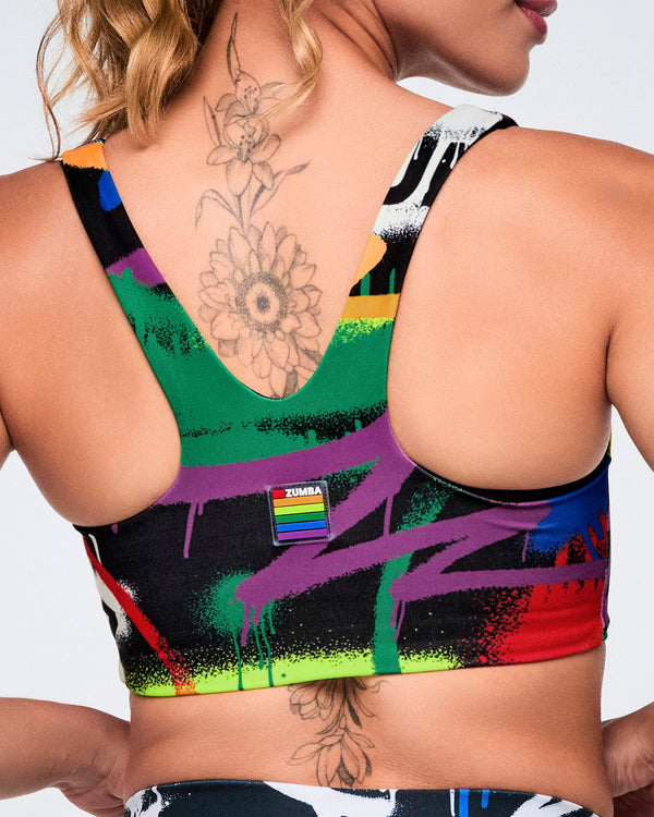 Colorful sports bra with abstract design and rainbow flag on a white background.