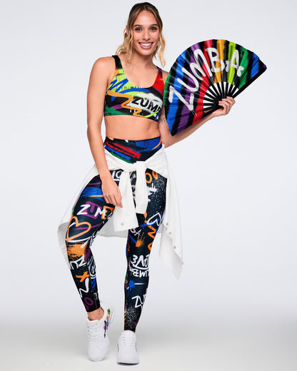 Female model wearing colorful Zumba outfit with a fan on a white background.