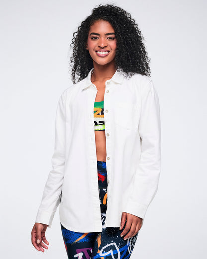 Female model wearing a white button down over a colorful bra and matching leggings on a white background.