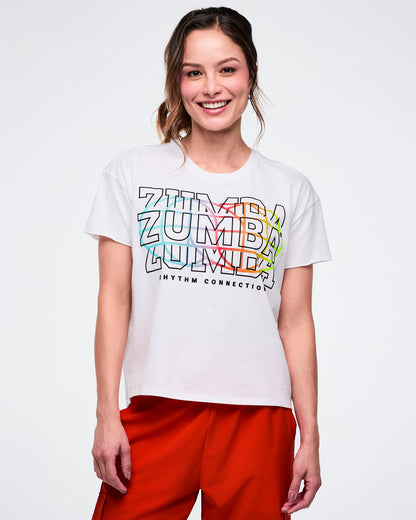 Female model in a white Zumba T-shirt with “Zumba” repeated three times, “Rhythm Connection” in black beneath, and a colorful globe icon on the back, set against a white background.