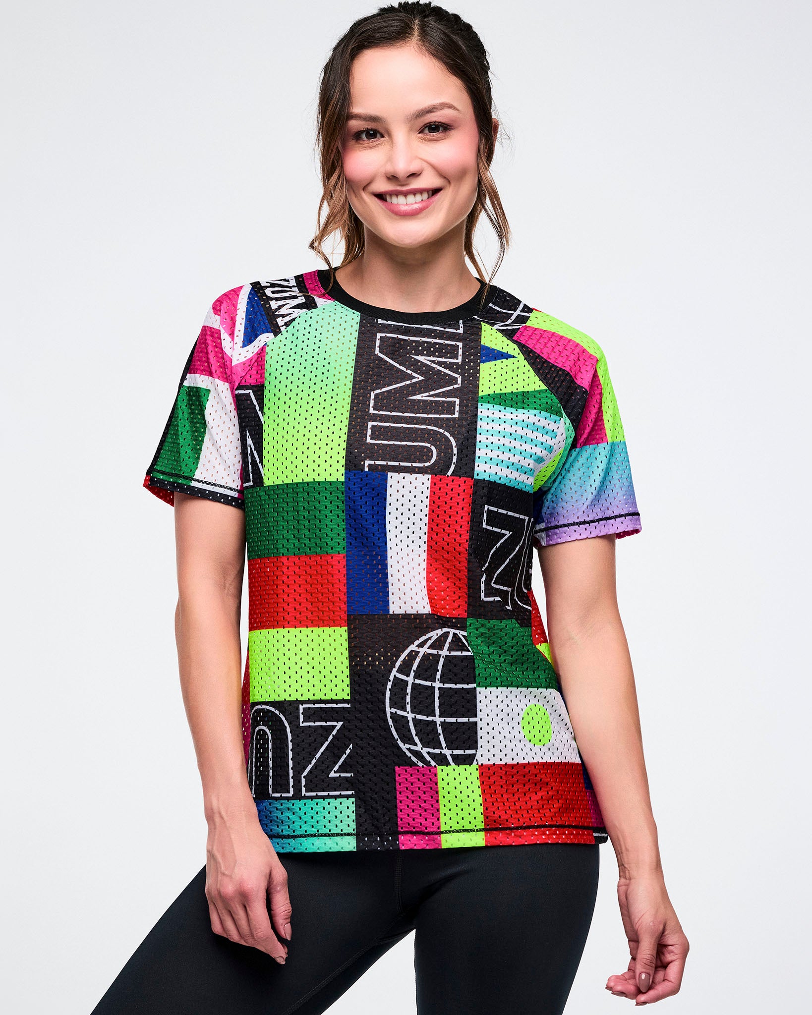 Female model wearing a colorful mesh crew neck top on a white background.