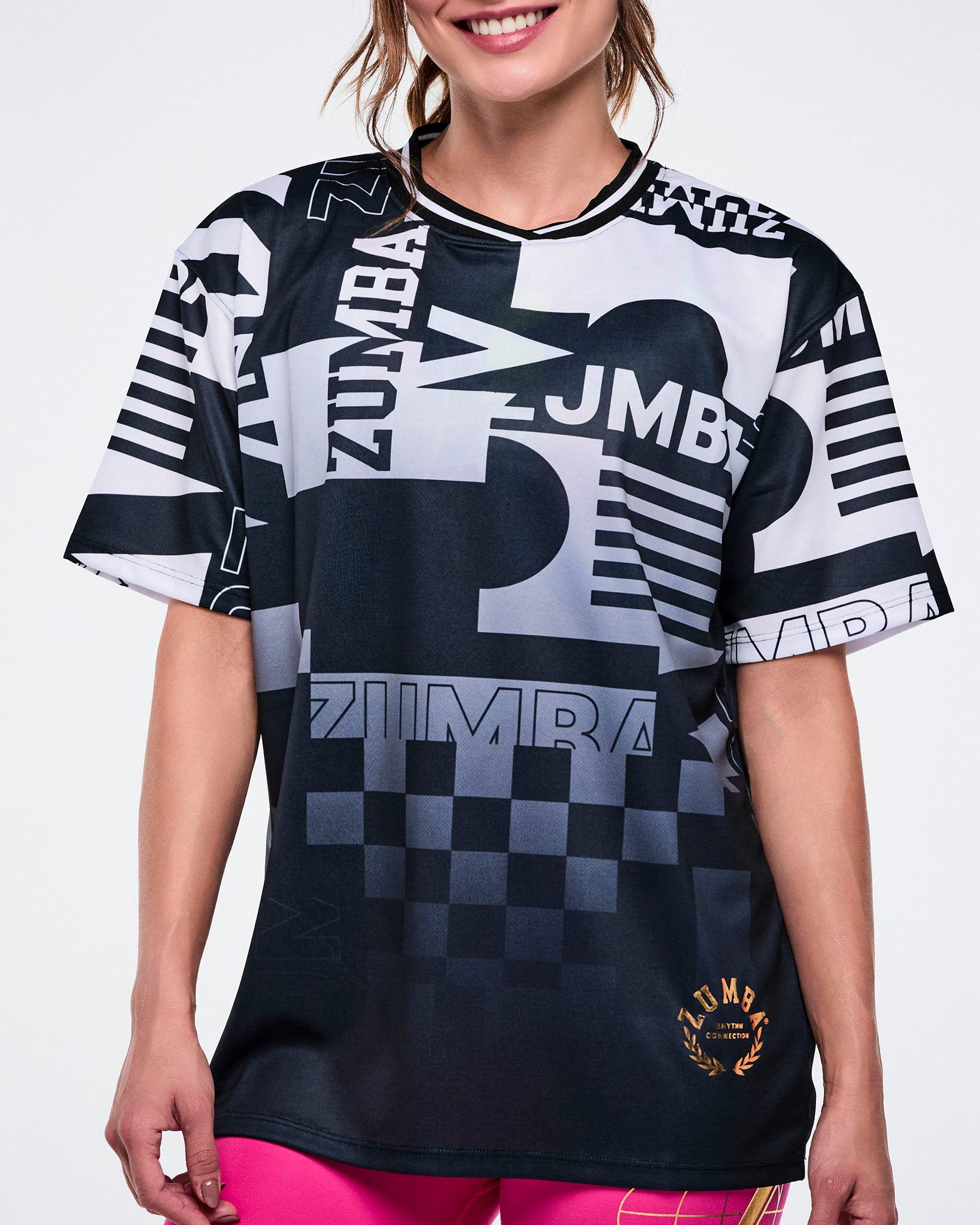 Close up of a female model wearing a black and white Zumba shirt with various patterns on a white background.