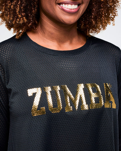 Close-up view of a black mesh top with "ZUMBA" in gold letters on a plain background.