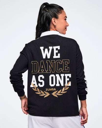 Female model wearing a black Zumba polo with 'We Dance As One' Zumba text on the back.