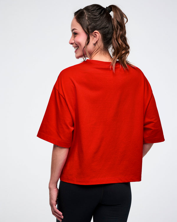 Back view of a female model wearing a red oversized top on a white background.