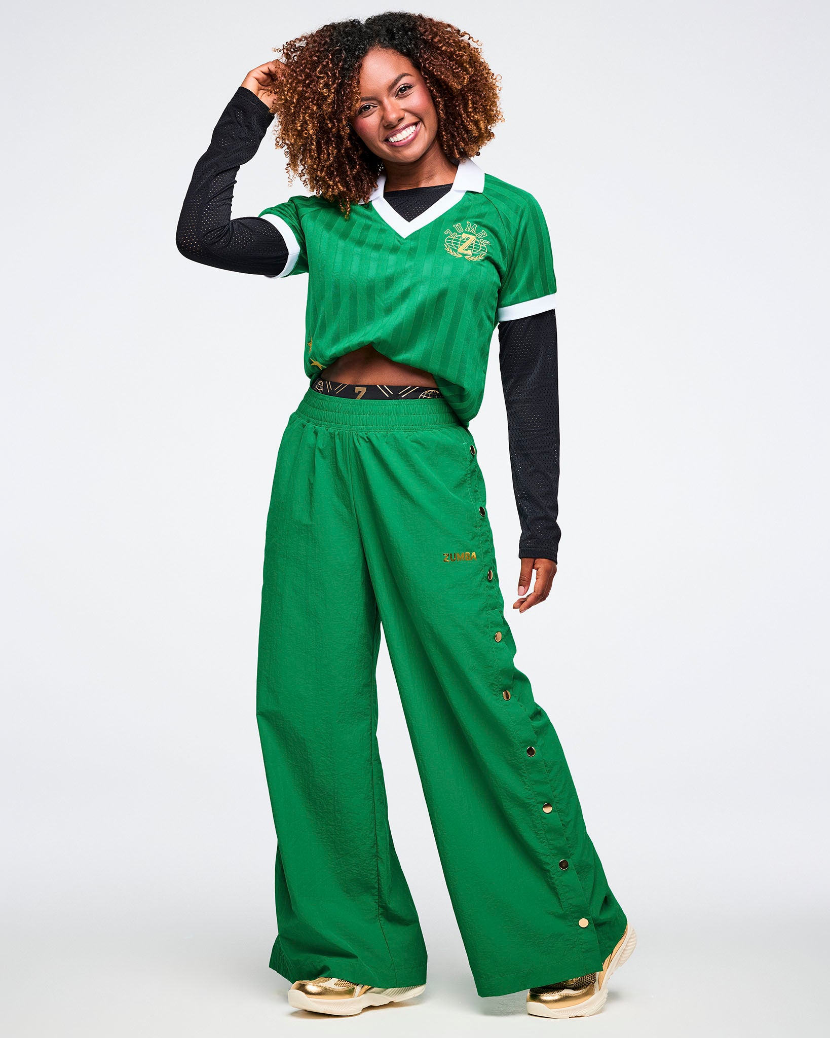 Female model wearing a green polo top and green snap pants against a white background.