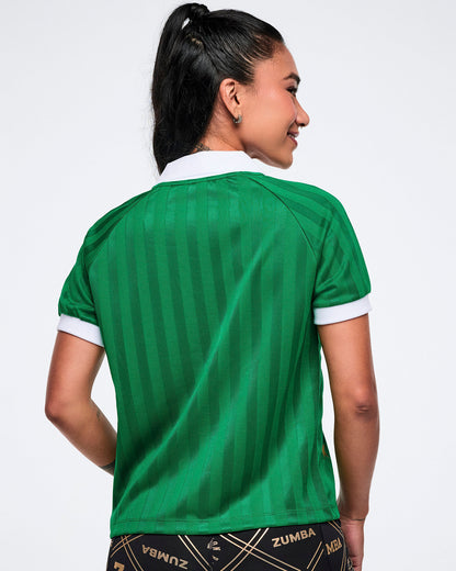 Back view of a female model in a green polo with white-trim collar and sleeves against a white background.