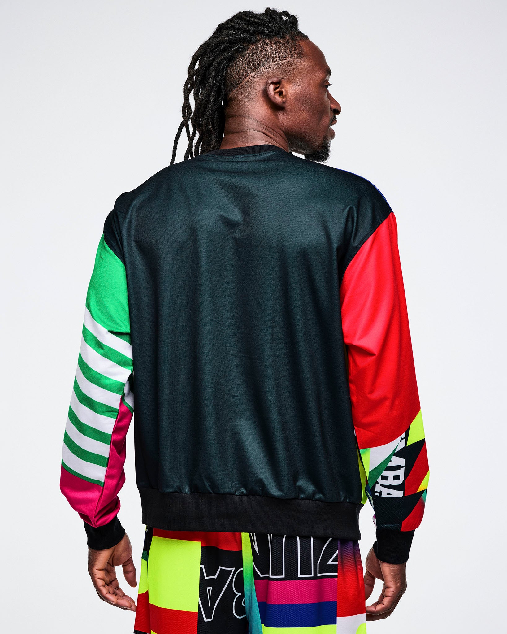 Back view of a male model in a black top with colorful sleeves, set against a white background.
