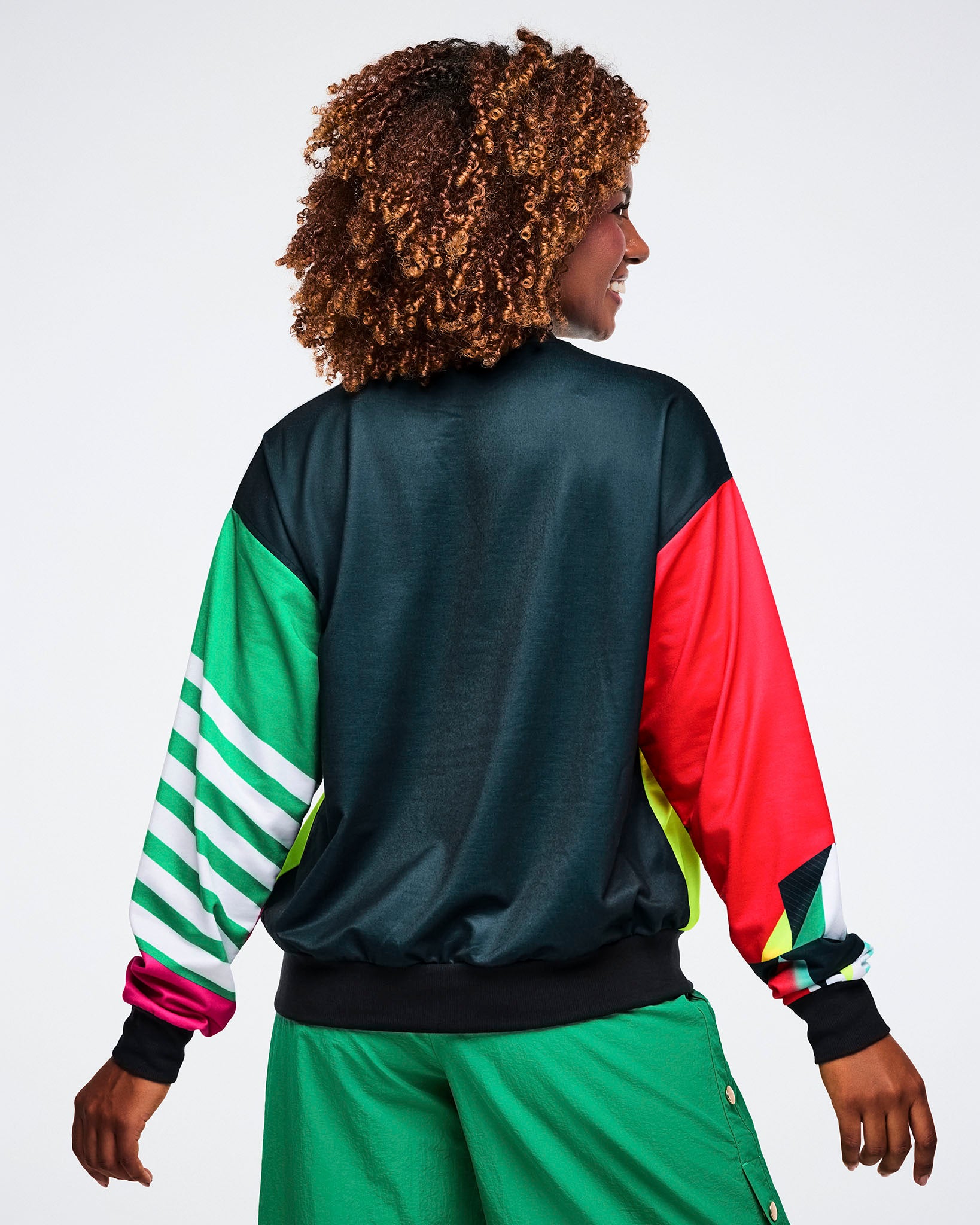 Back view of a female model wearing a black shirt with colorful sleeves on a white background.