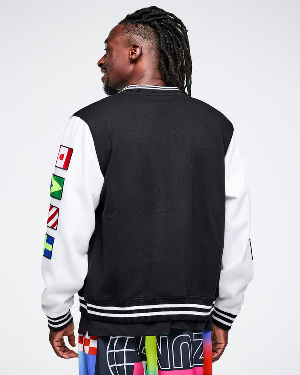 Back view of a male model wearing a black and white varsity jacket with colorful flag designs on a white background.