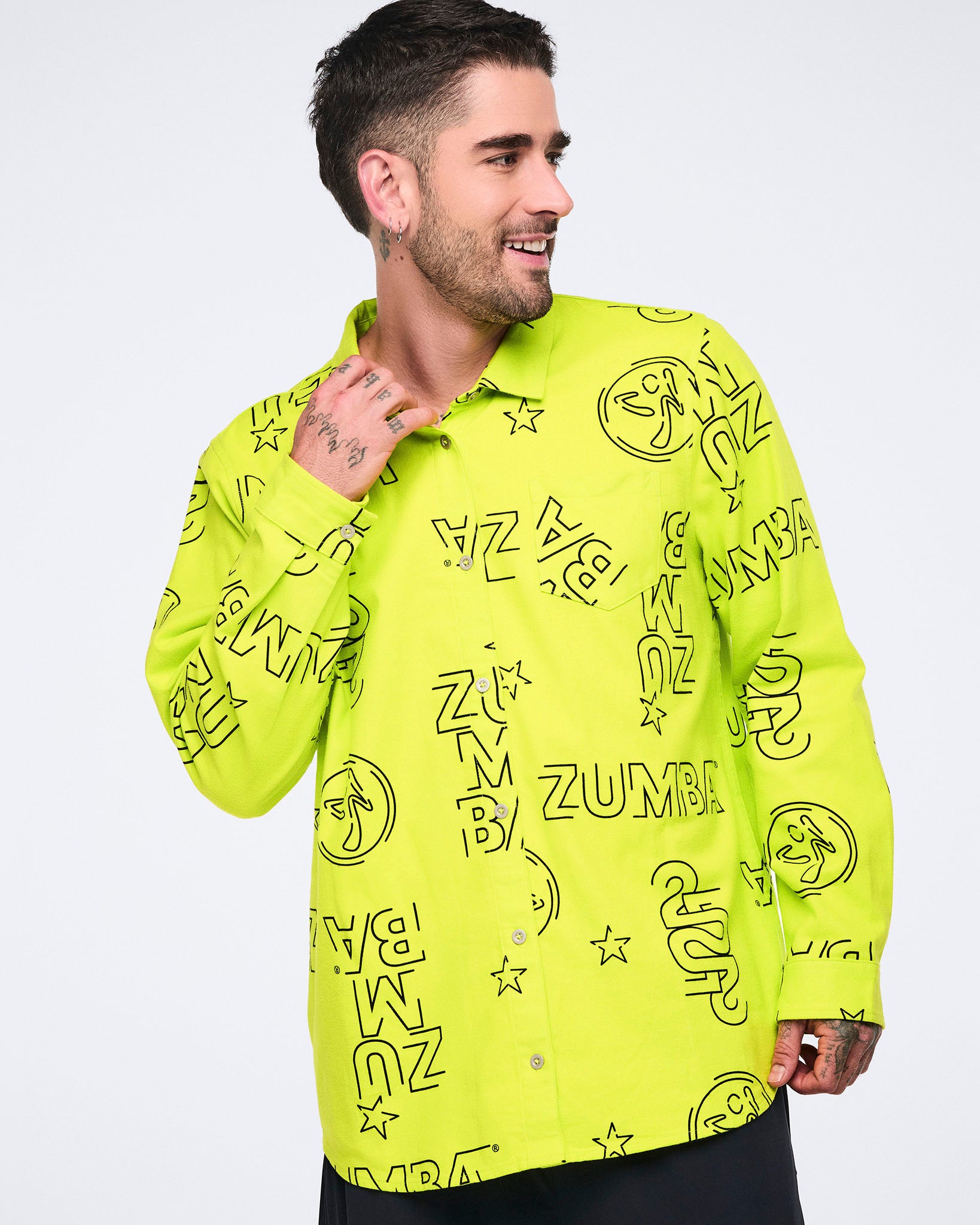 Neon green long-sleeve button-down shirt with black allover Zumba logo print. Male model wears the relaxed collared shirt with black pants, shown in a front view against a light gray background.