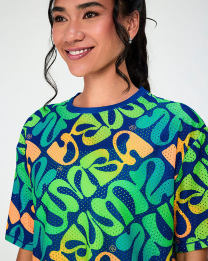 Close-up of the blue warped 'ZUMBA' print mesh top, showing the open-hole mesh, the blue neckband, and small Zumbito logos scattered through the print.