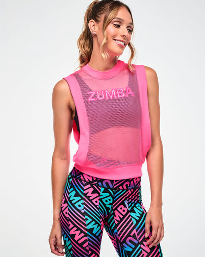 Female model wearing a pink mesh tank with "ZUMBA" text, paired with black, pink, and aqua striped "ZUMBA" print leggings.