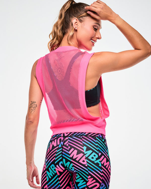 Shown from the back with a black sports bra visible, female model wearing a pink tank, paired with black, pink, and aqua striped leggings.