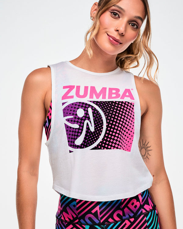 Close-up of a white cropped tank with pink 'ZUMBA' text and a purple, black, and pink dot pattern with a white Zumbito logo.